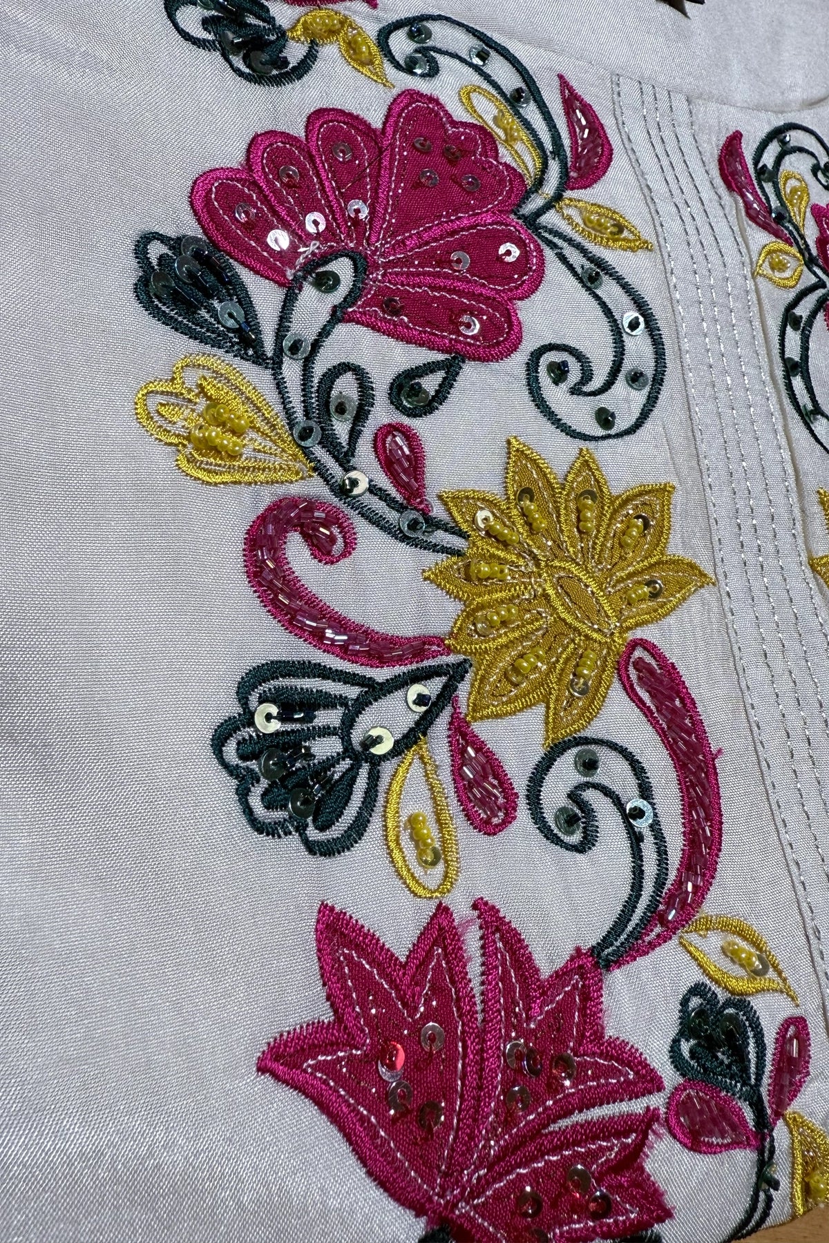 Close-up of embroidered fabric with flowers and butterflies on a white background