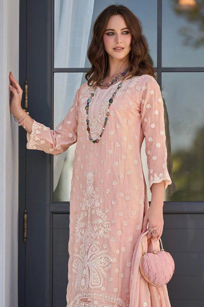 Woman wearing a pink embroidered kurta set with a necklace, standing indoors.Woman wearing a pink embroidered kurta set with a necklace, standing indoors.