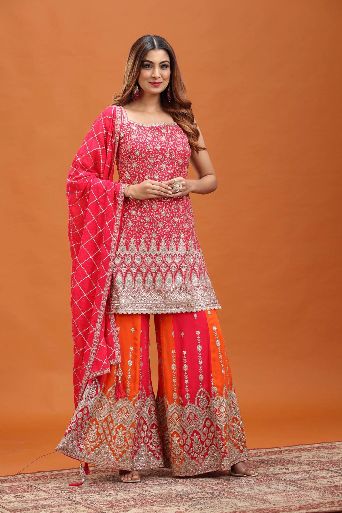 Woman wearing a traditional outfit with a pink and orange design against an orange background