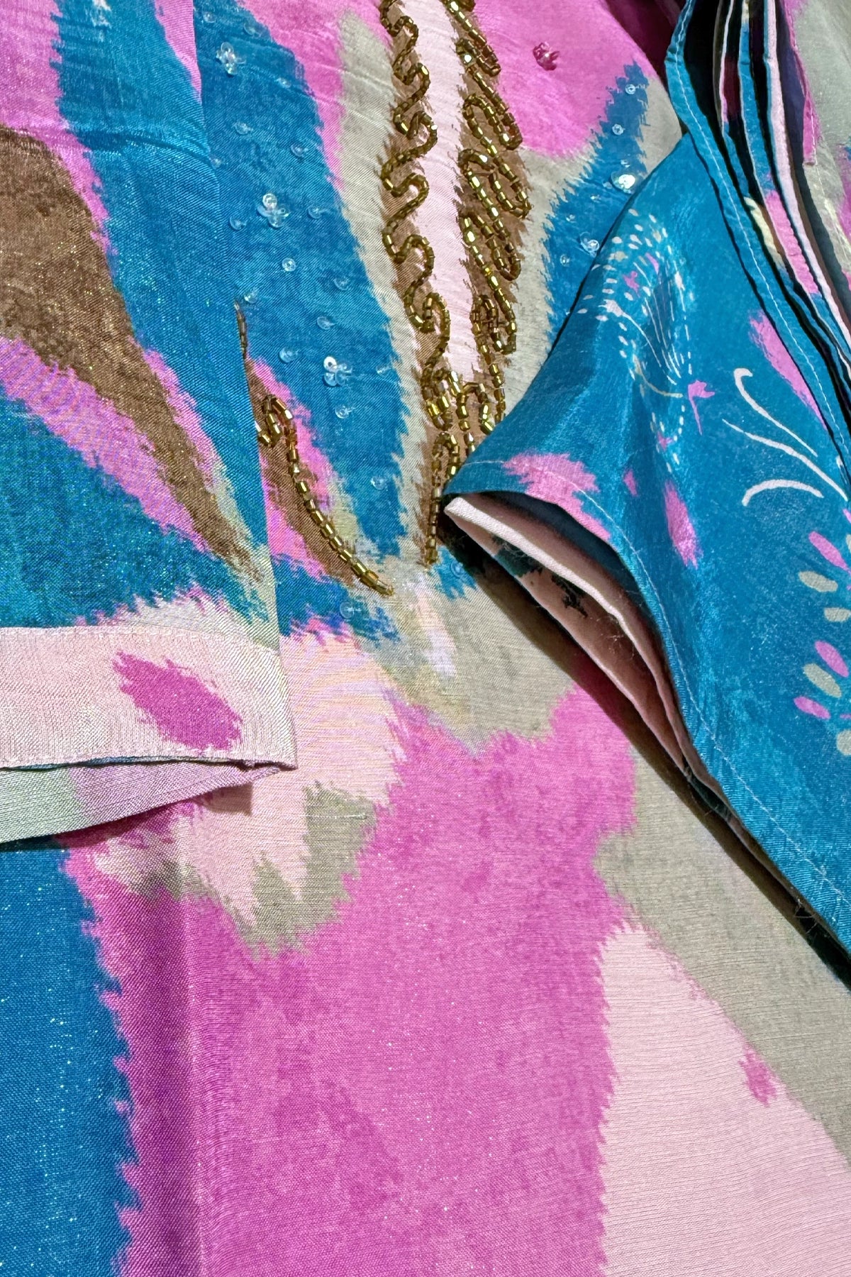 Close-up of a colorful pink Indian Dress with abstract patterns and a gold embroidery.