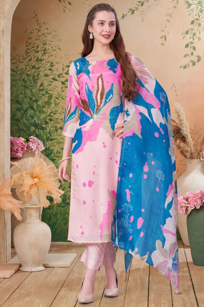 Woman wearing a colorful floral Indian dress with a blue dupatta in a decorated indoor setting.