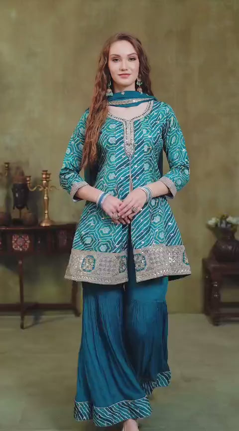 Woman wearing a teal blue traditional salwar suit outfit with gold embroidery in a studio setting.