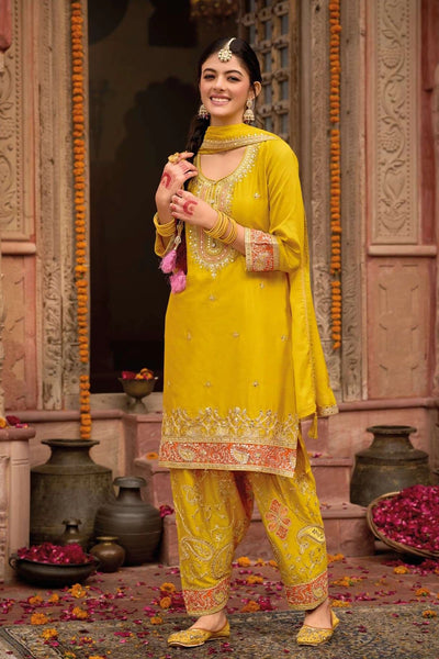 Woman in a yellow traditional punjabi outfit standing in front of an ornate architectural background.Woman in a yellow traditional punjabi outfit standing in front of an ornate architectural background.