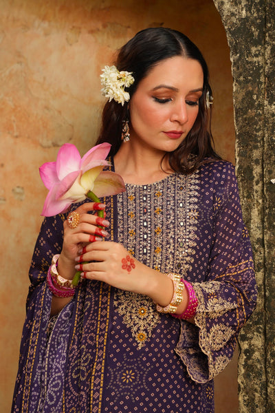 Woman in traditional embroidered outfit holding a pink flower against a textured wall.Woman in traditional embroidered outfit holding a pink flower against a textured wall.