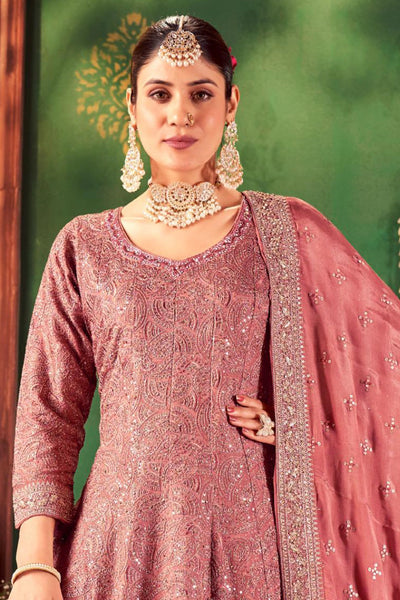 Woman in traditional pink embroidered anarkali outfit with jewelry against a green backgroundWoman in traditional pink embroidered anarkali outfit with jewelry against a green background