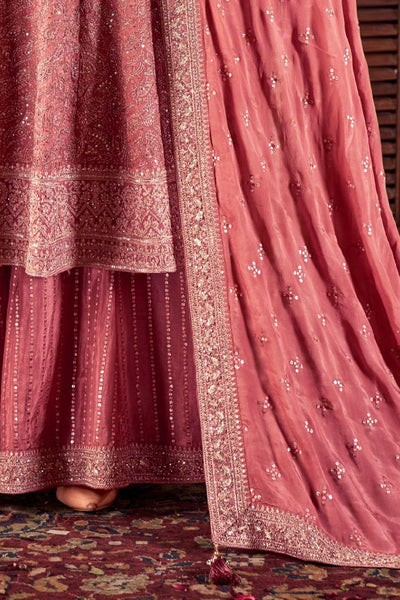 Close-up of a rose pink embroidered traditional outfit with intricate patterns.Close-up of a rose pink embroidered traditional outfit with intricate patterns.