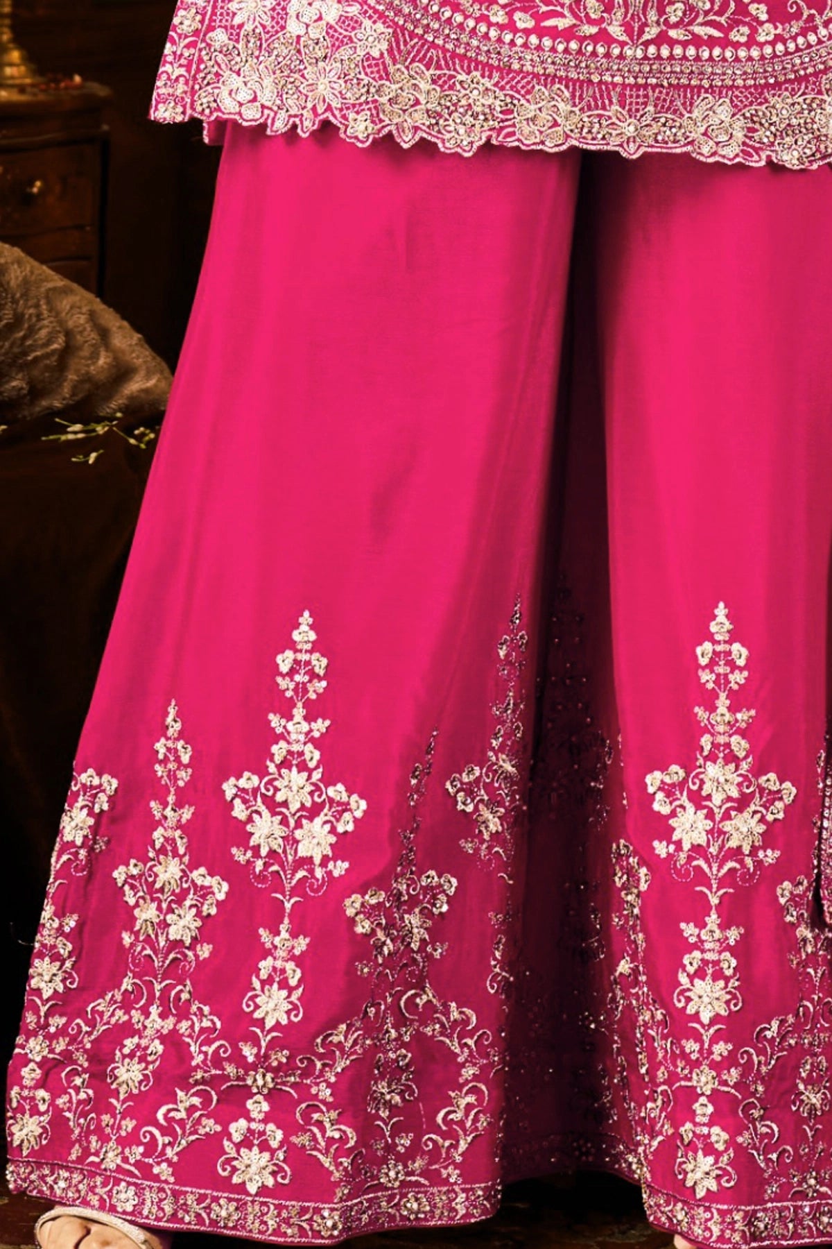 Pink traditional sharara outfit with white embroidery on a dark background