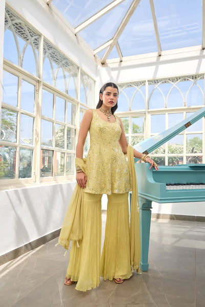 Woman in a Light Yellow Georgette Sharara Suit traditional outfit standing next to a blue piano in a conservatory.Woman in a Light Yellow Georgette Sharara Suit traditional outfit standing next to a blue piano in a conservatory.